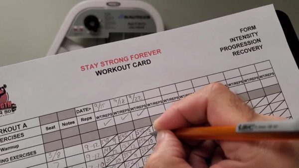 recording strength training progress on a workout card - strength after 50 
