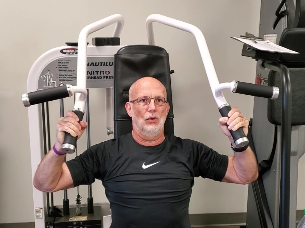 Dave Durell from Strength After 50 performing a shoulder press on a nautilus machine for gaining muscle after 50