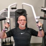 Dave Durell from Strength After 50 performing a shoulder press on a nautilus machine for gaining muscle after 50