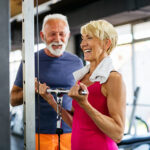 Couple performing strength training for seniors exercise in the gym